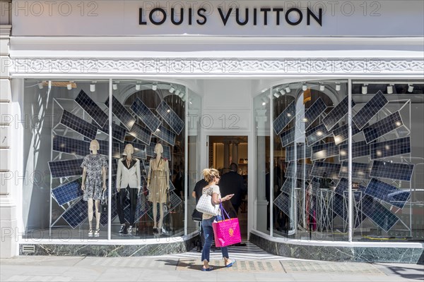 Passers-by in front of the shop window of the fashion store Louis Vuitton