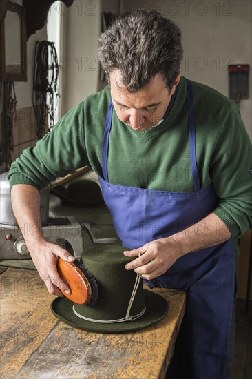 Man brushing a dry wool felt hat