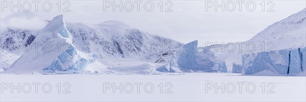 Panoramic view of snow-covered mountains seen from a frozen fjord