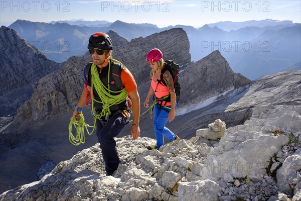 Mountain guide guiding a young woman on a short rope through a rock face