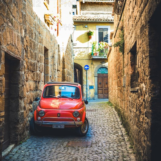 Old red Fiat 500 parked in a narrow alley