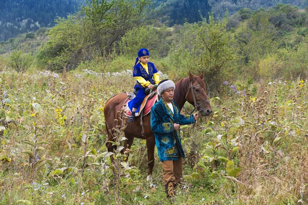 Kazakh man walking around with his son on a horse after Circumcision Sundet Toi ceremony