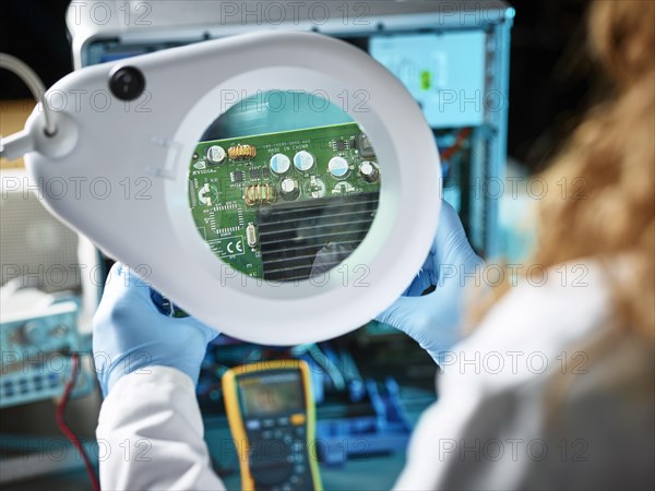Engineer with white lab coat examining graphics card