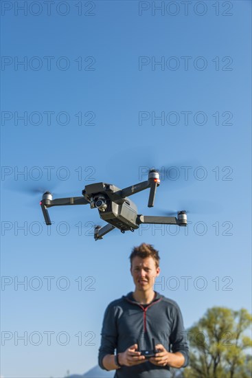 Young man controlling flying quadrocopter