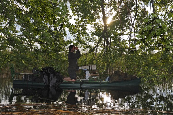 Nature photographer on boat with binoculars