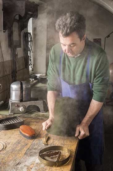 Man fitting wet hat body to wooden form