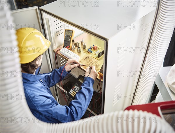 Engineer with helmet during a repair and troubleshooting of control of a CNC machine