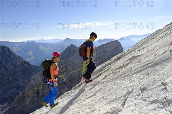 Mountain guide guiding a young woman on a short rope through a rock face