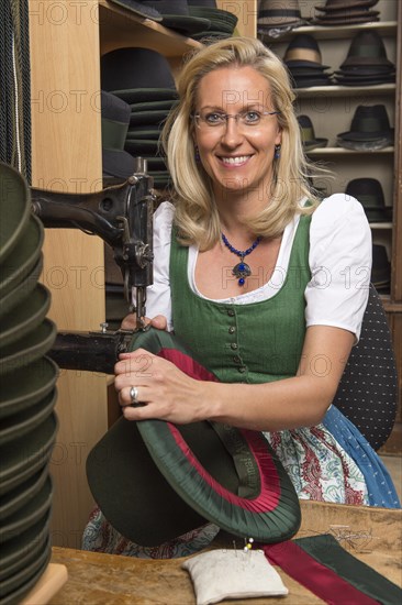 Woman sewing silk ribbon and inner lining on hat edge