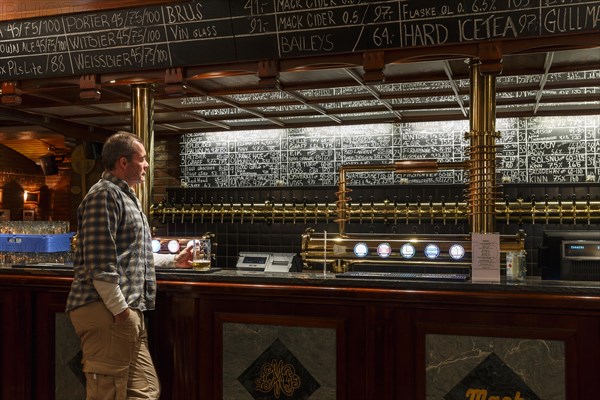 Man holding a glass of beer at Olhallen