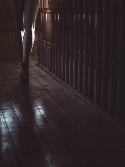 Bare legs of a woman walking barefoot along staircase railing