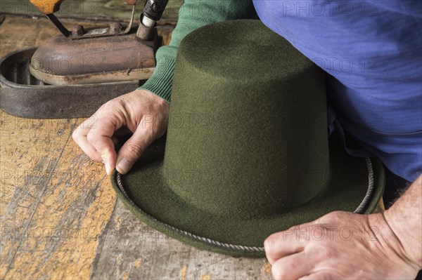 Hands holding cord on dry wool felt hat with shaped edge