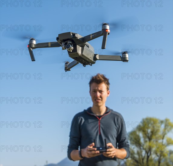 Young man controlling flying quadrocopter