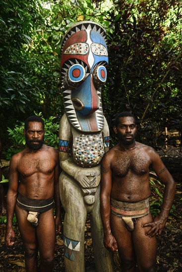 Two native men with totem pole