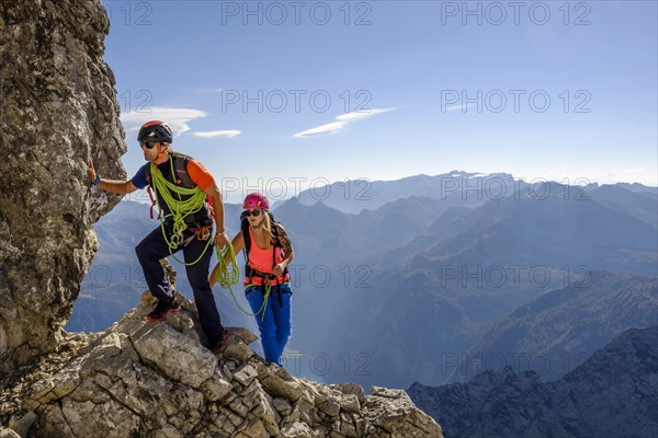 Mountain guide guiding a young woman on a short rope through a rock face