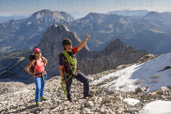 Mountain guide guiding a young woman on a short rope through a rock face