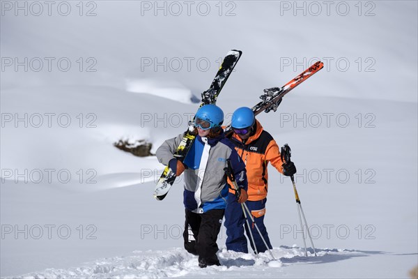 Skiers walking with shoulderd skis in the snow