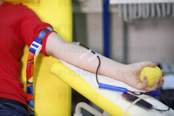 Patient with an infusion needle taking a blood sample at the transfusion ward of a hospital