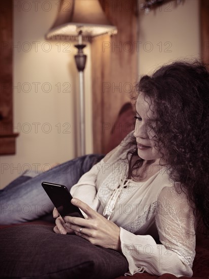 Young woman lying an a sofa holding an Apple iPhone 7 Plus