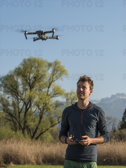 Young man controlling flying quadrocopter