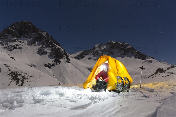 Snowshoe hikers in an illuminated tent in the snow on the Madelejoch