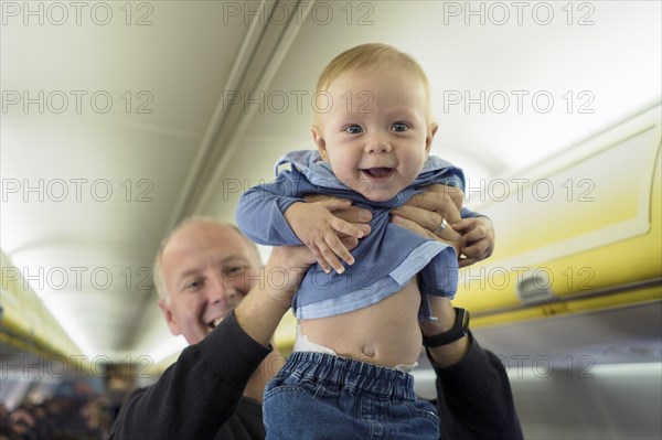 Father standing with his six months old baby boy in the airplane
