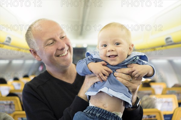 Father standing with his six months old baby boy in the airplane