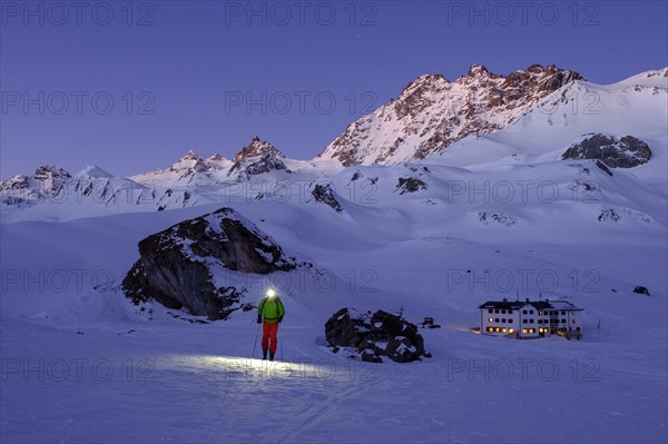 Ski tourer with headlamp in front of Heidelberger Hutte