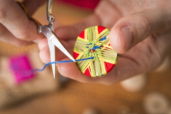 Button maker cutting blue yarn