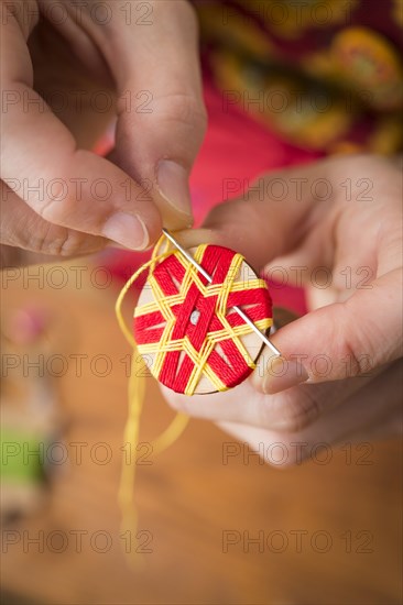 Button maker stitching and wrapping red and yellow yarn into star pattern