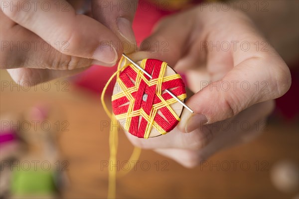 Button maker stitching and wrapping red and yellow yarn into star pattern