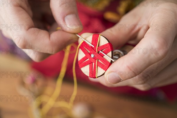 Button maker stitching and wrapping red and yellow yarn into star pattern