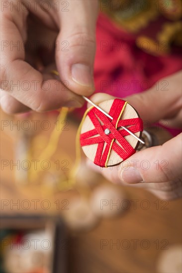 Button maker stitching and wrapping red and yellow yarn into star pattern