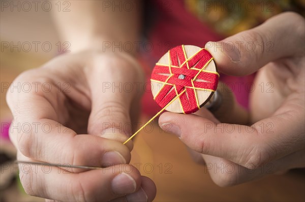 Button maker stitching and wrapping red and yellow yarn into star pattern