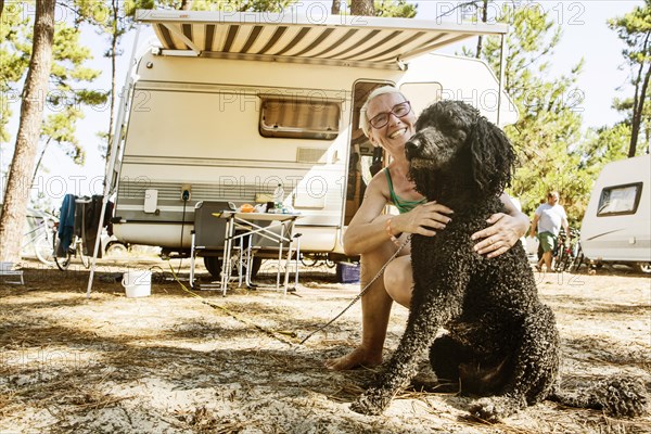 Woman squats laughing with her dog