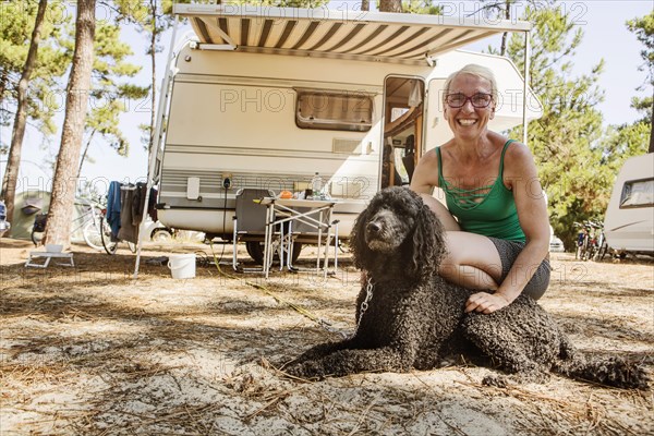 Woman squats laughing with her dog