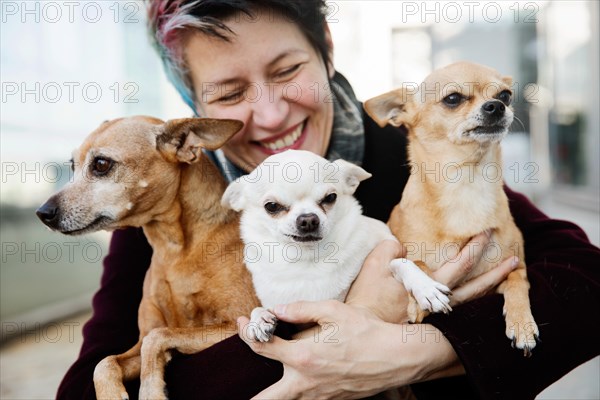 Laughing woman holding her three dogs in her arms