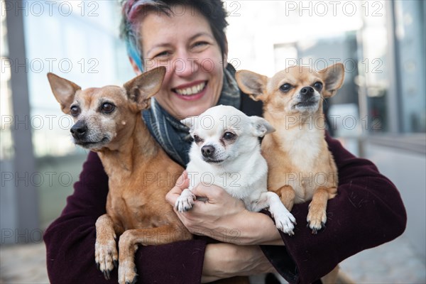 Laughing woman holding her three dogs in her arms