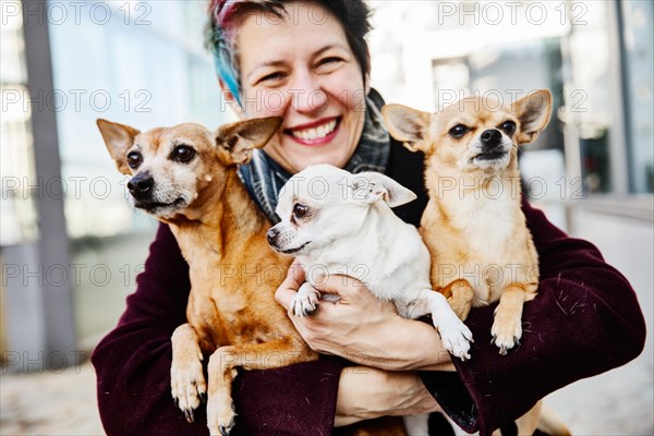 Laughing woman holding her three dogs in her arms