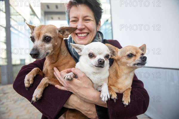 Laughing woman holding her three dogs in her arms