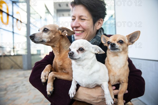Laughing woman holding her three dogs in her arms