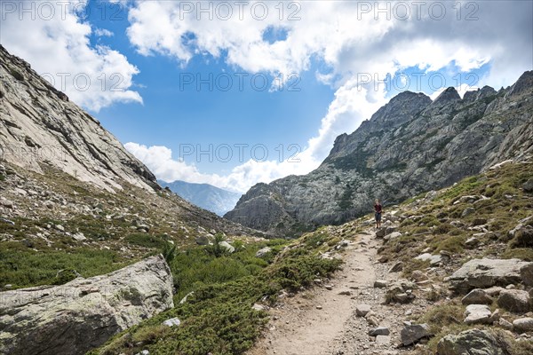 Young man hiking on a trail through the Golo Valley Nature Park of Corsica