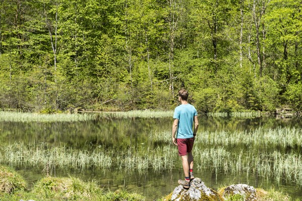 Young man standing on stone at lake