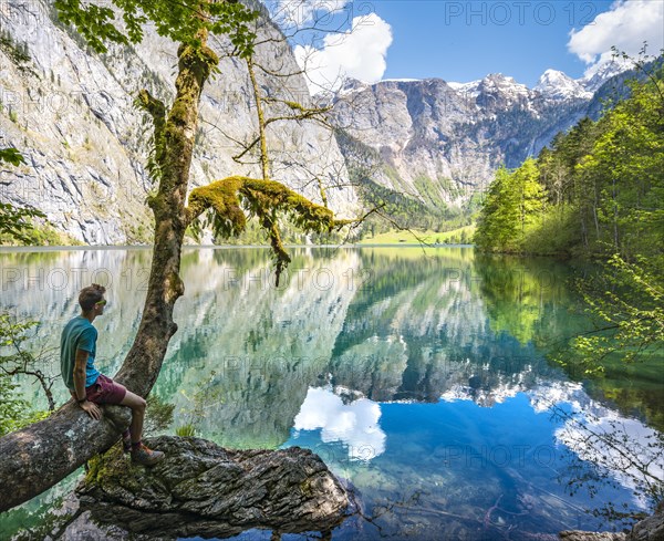 Young man sitting on tree above water