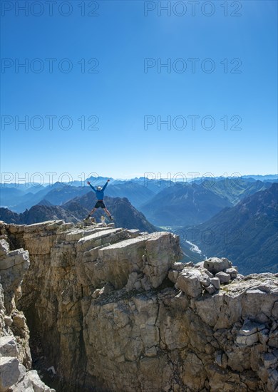 Hiker jumps and stretches arms into the air