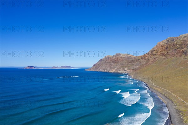 View on beach Playa Famara with mountain range Risco de Famara