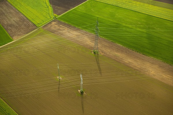 High-voltage transmission lines over farm fields in spring