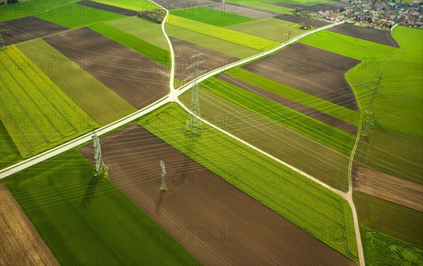 High-voltage transmission lines over farm fields in spring