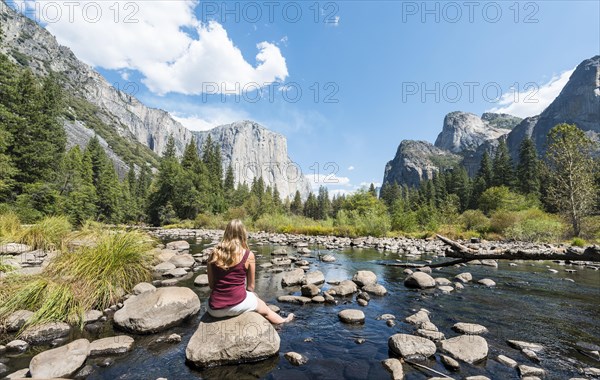 Young woman sitting on stone in River Merced