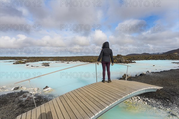 Tourist on a wooden bridge at the Blue Lagoon near Gratdavik